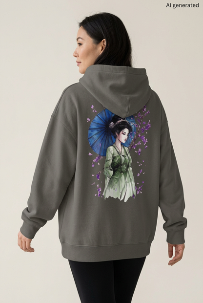 Frau mit asphaltgrauem Oversized-Hoodie, Rückenmotiv einer Maiko im grünen Kimono mit blauem Schirm und violetten Blüten. KI-generiertes Mockup.